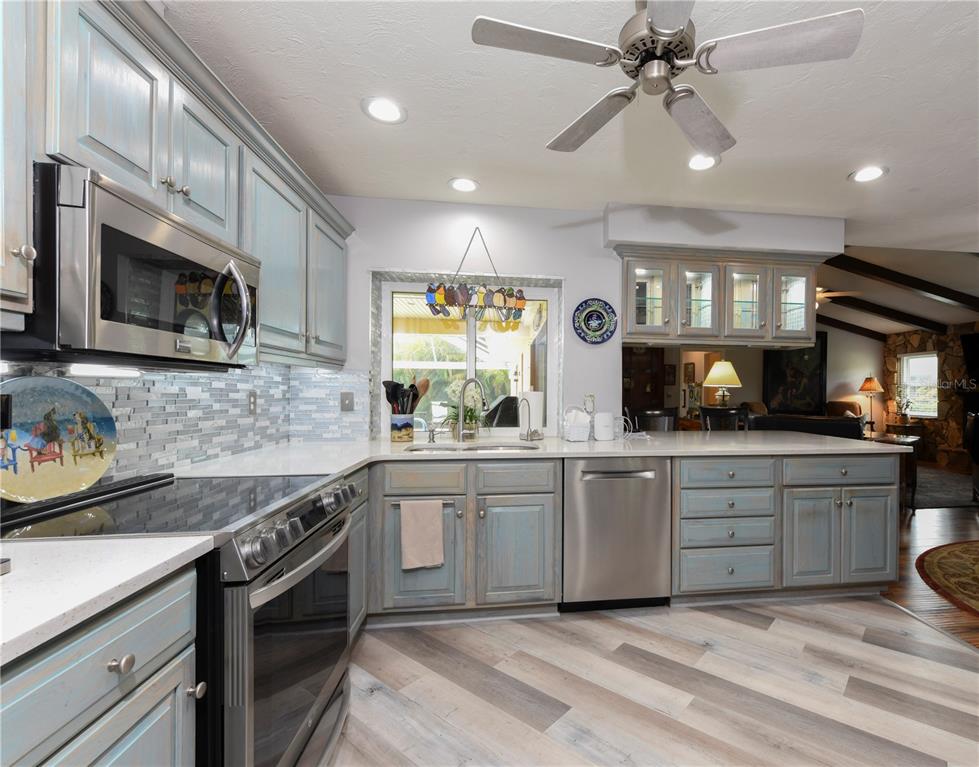 A kitchen with light blue cabinets, stainless steel appliances, and a glass-tiled backsplash — 1800 LIESL DRIVE E, VENICE, FL