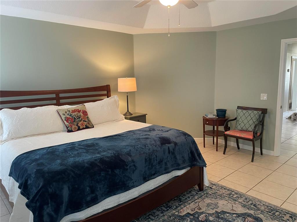 A bedroom features a king bed, a dark wood chair, and tile flooring — 319 NIBLICK CIRCLE, WINTER HAVEN, FL