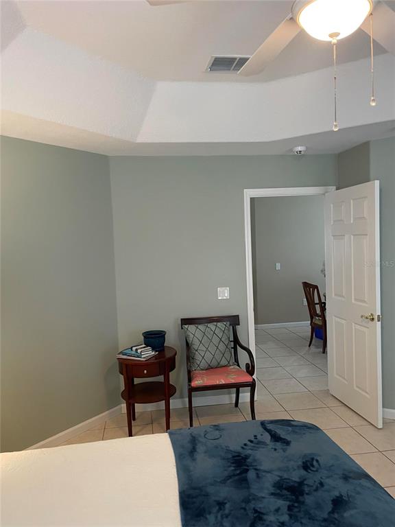 A bedroom features a tray ceiling, light green walls, tile flooring, and an open doorway — 319 NIBLICK CIRCLE, WINTER HAVEN, FL