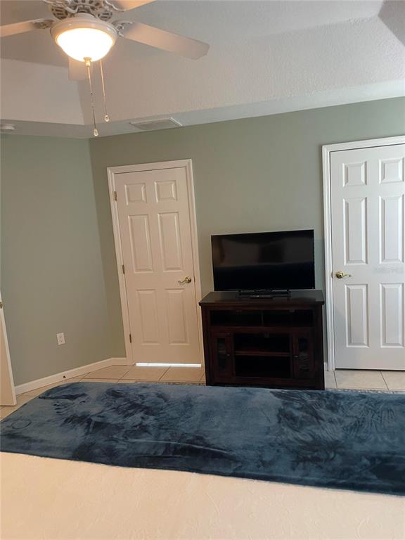 A bedroom features a ceiling fan, a television on a dark wood stand, and two doors — 319 NIBLICK CIRCLE, WINTER HAVEN, FL