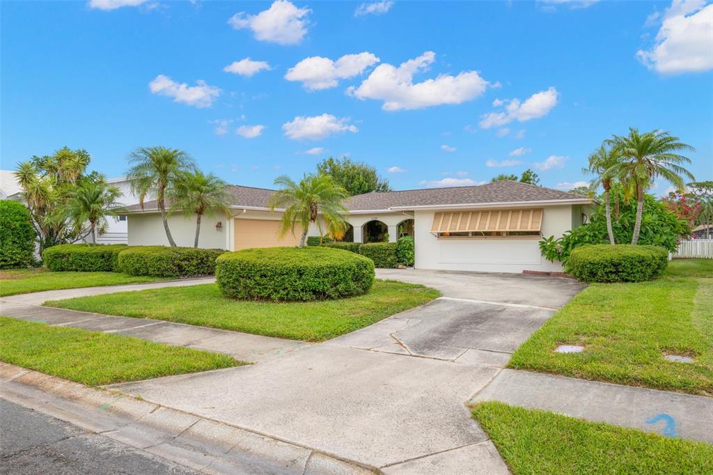A single-story house with a beige exterior, a two-car garage, and a landscaped front yard — 6729 TEQUESTA DRIVE, SEMINOLE, FL