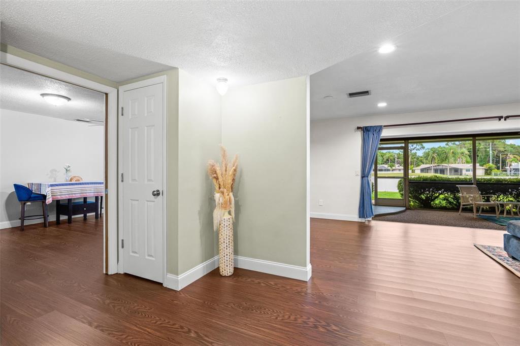 A view of a living area with wood-look flooring, a white door, and a sunroom — 6729 TEQUESTA DRIVE, SEMINOLE, FL