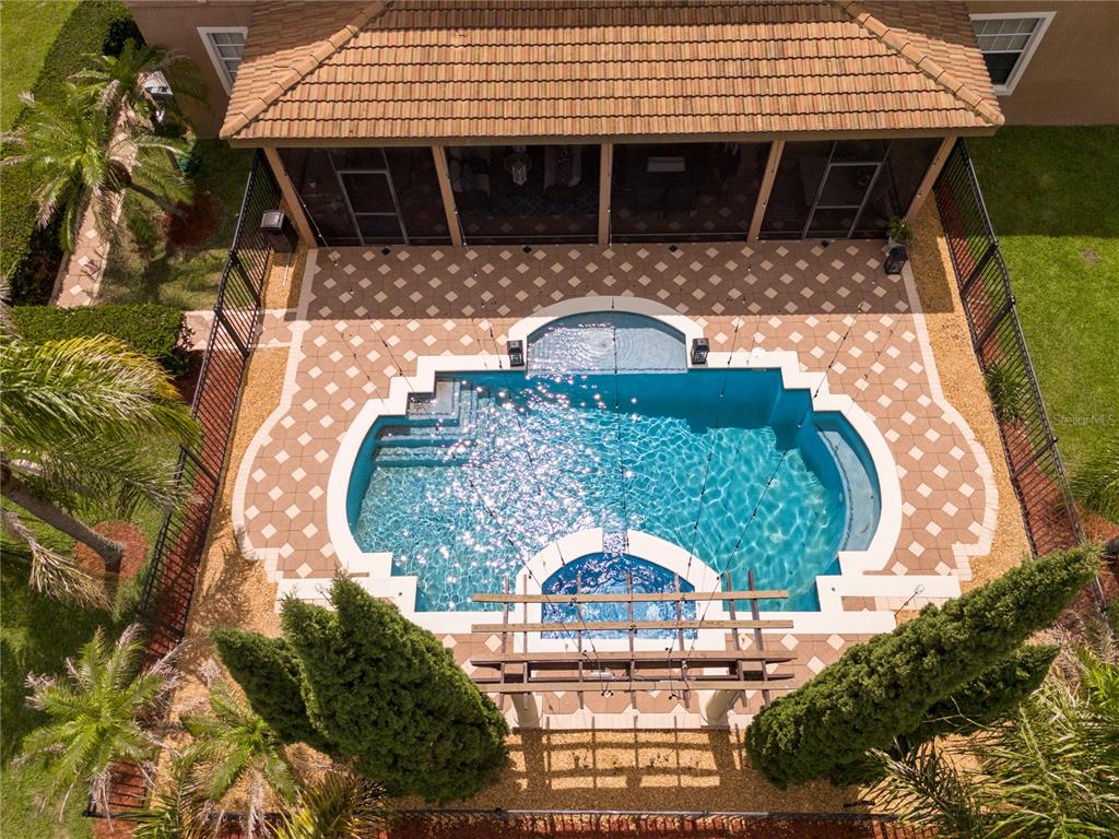 An aerial view shows a swimming pool with a spa and pergola inside a screened enclosure — 5741 OXFORD MOOR BOULEVARD, WINDERMERE, FL