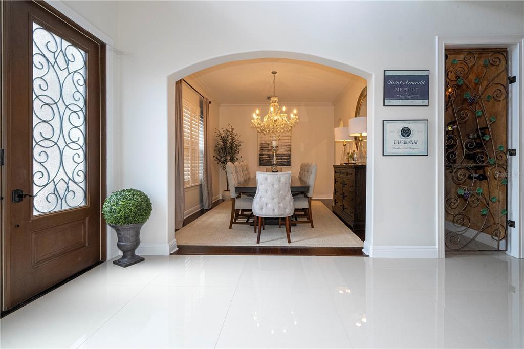 A dining room with a crystal chandelier is visible through an arched entryway from a foyer — 5741 OXFORD MOOR BOULEVARD, WINDERMERE, FL