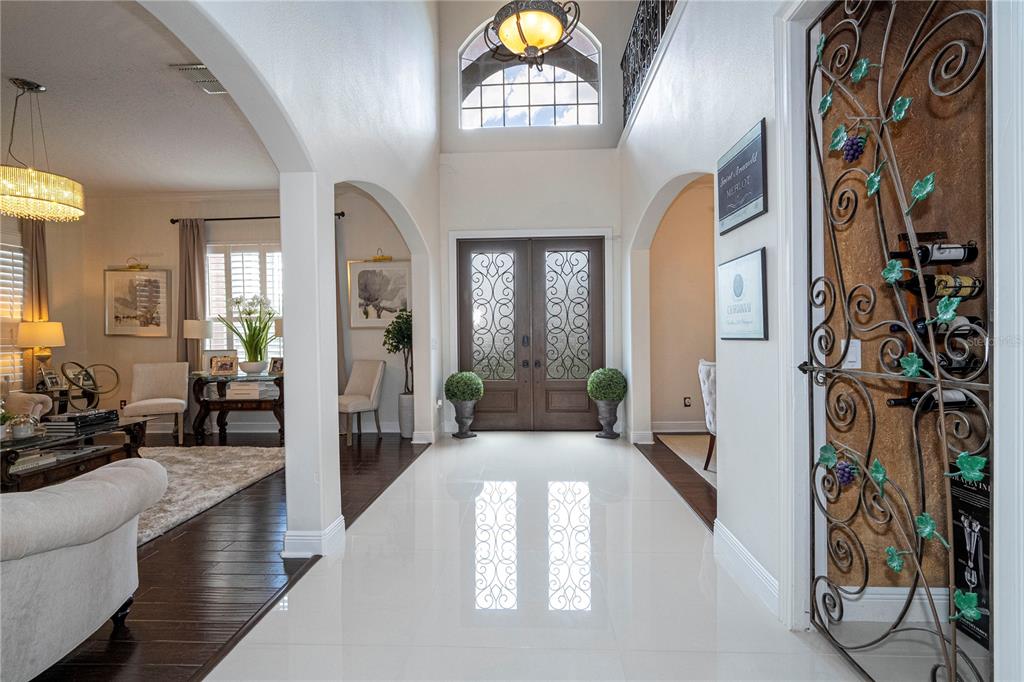 A bright foyer features white tile floors, arched entryways, and a decorative metal wine rack — 5741 OXFORD MOOR BOULEVARD, WINDERMERE, FL