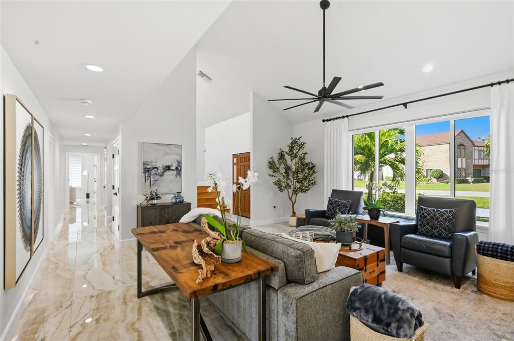 A living room features a vaulted ceiling, large windows, tile flooring, and a wooden console table — 1307 RIVERVIEW CIRCLE, BRADENTON, FL