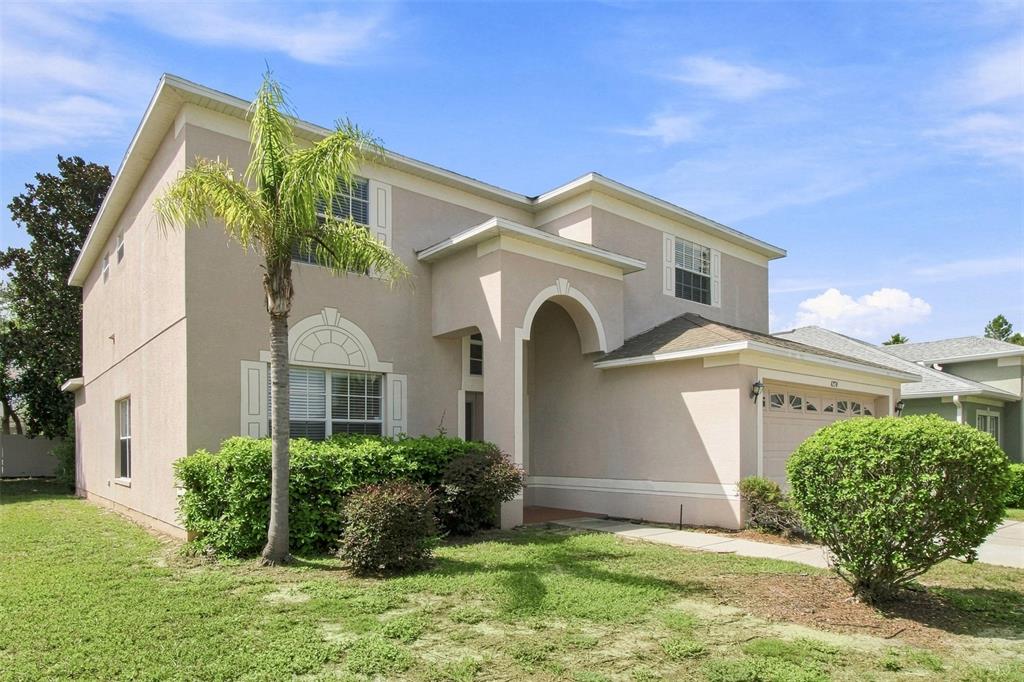A two-story beige stucco house with a palm tree, arched entryway, and attached garage — 4276 BRAEMERE DRIVE, SPRING HILL, FL