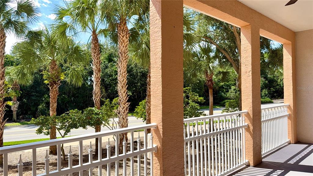 A covered balcony features white railings, stucco columns, and a view of palm trees — 35 OCEAN CREST WAY UNIT 1113, PALM COAST, FL