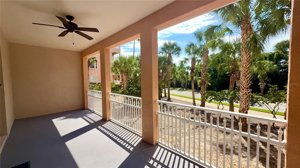 A covered balcony with a ceiling fan, white railings, and a view of palm trees — 35 OCEAN CREST WAY UNIT 1113, PALM COAST, FL