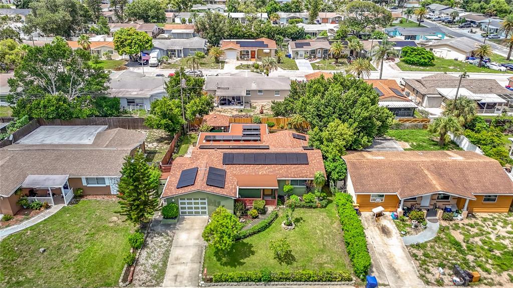 An aerial view shows a residential neighborhood featuring a house with solar panels on its roof — 3641 WELLINGTON DR, HOLIDAY, FL