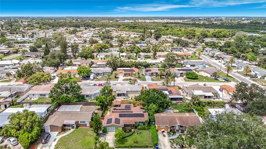 An aerial view shows a residential neighborhood with single-story houses and solar panels on roofs — 3641 WELLINGTON DR, HOLIDAY, FL