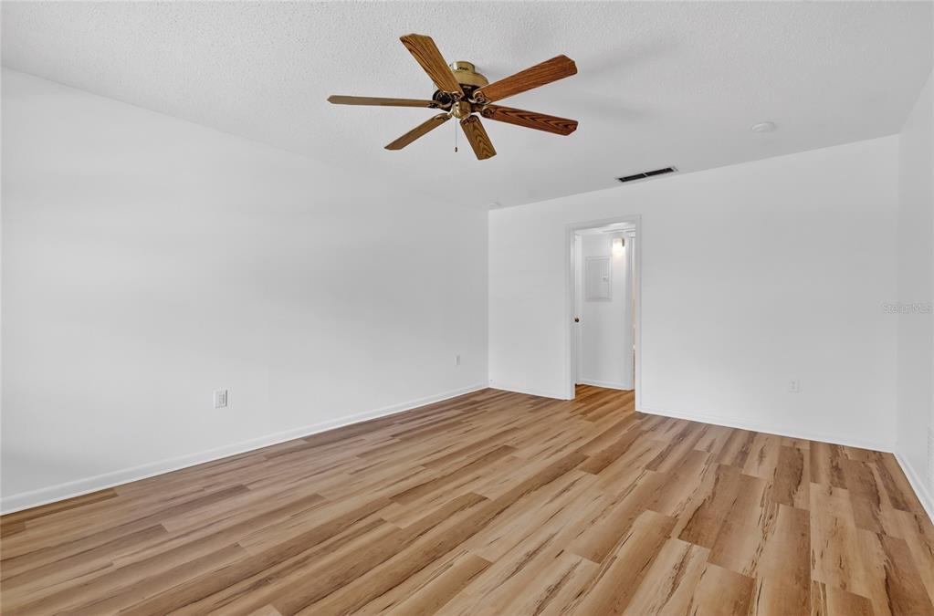 An empty room with white walls, wood-look flooring, and a ceiling fan — 200 E 10TH AVENUE UNIT 8, MOUNT DORA, FL
