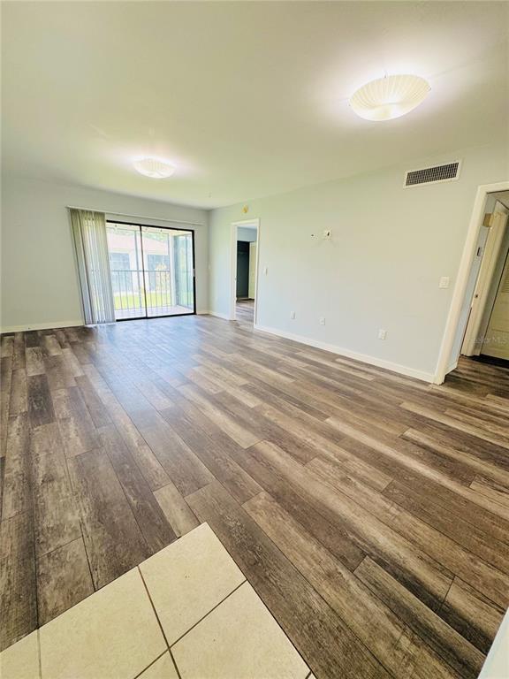 An open living area features wood-look flooring, two ceiling lights, and a sliding glass door — 106 WINDWARD PLACE, OLDSMAR, FL