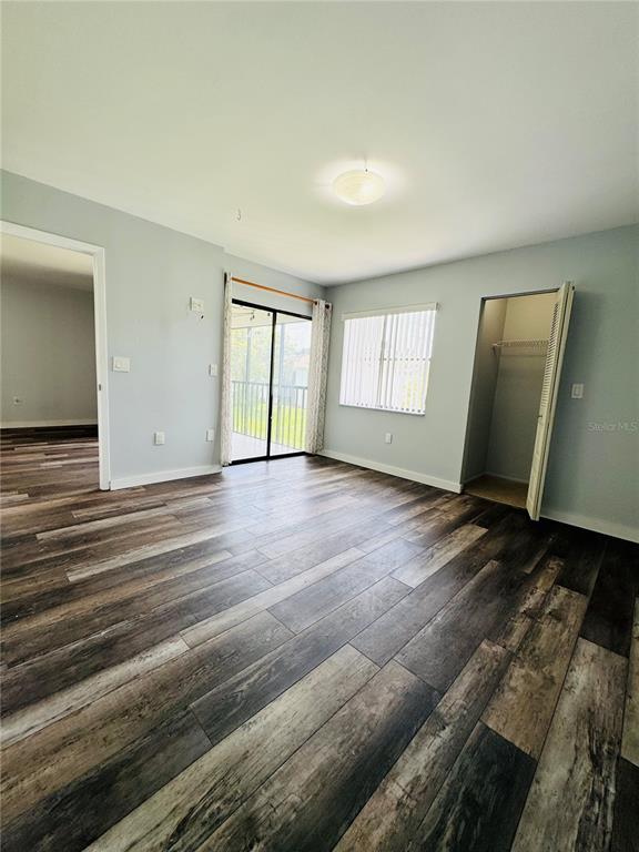 A bedroom with wood-look flooring, a sliding glass door to a patio, and a closet — 106 WINDWARD PLACE, OLDSMAR, FL