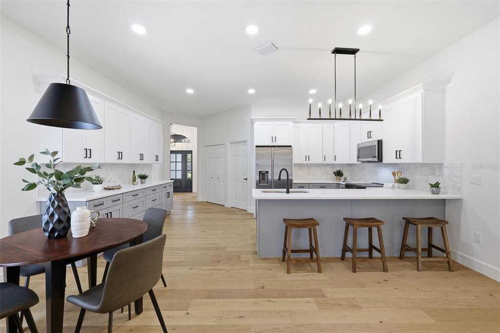 A modern kitchen features white cabinetry, a gray island with bar stools, and hardwood floors — 3040 WINDRIDGE OAKS DRIVE, PALM HARBOR, FL