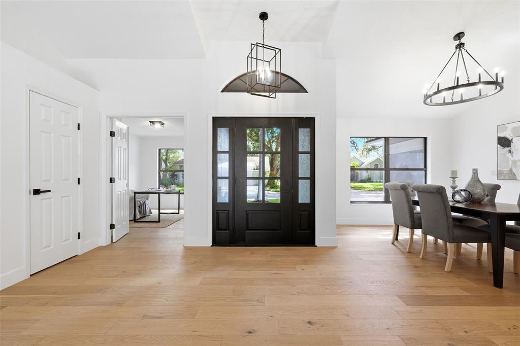 A bright entryway features light wood floors, a black front door, and a dining area — 3040 WINDRIDGE OAKS DRIVE, PALM HARBOR, FL
