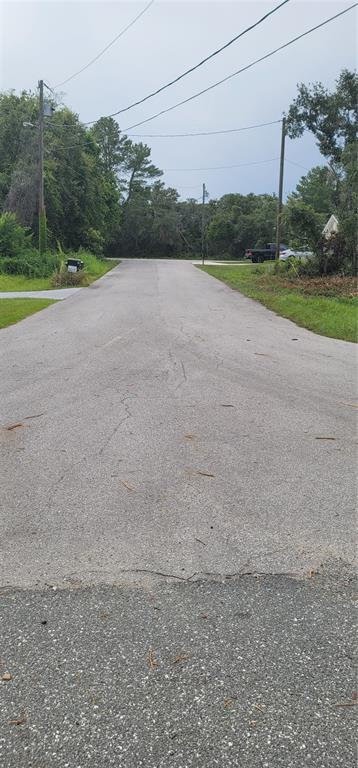 A paved residential street leads toward a wooded area with utility poles on both sides — Lot 15 OLIVE WAY, OCALA, FL