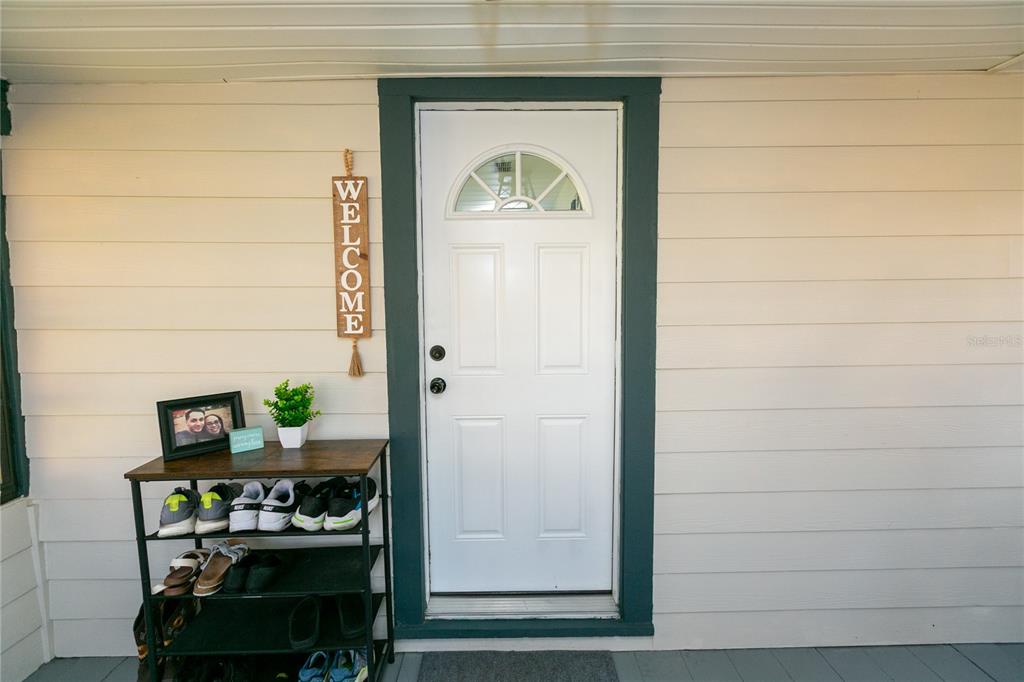 A white front door with a transom window is flanked by a shoe rack — 807 TENNESSEE AVENUE, ST CLOUD, FL