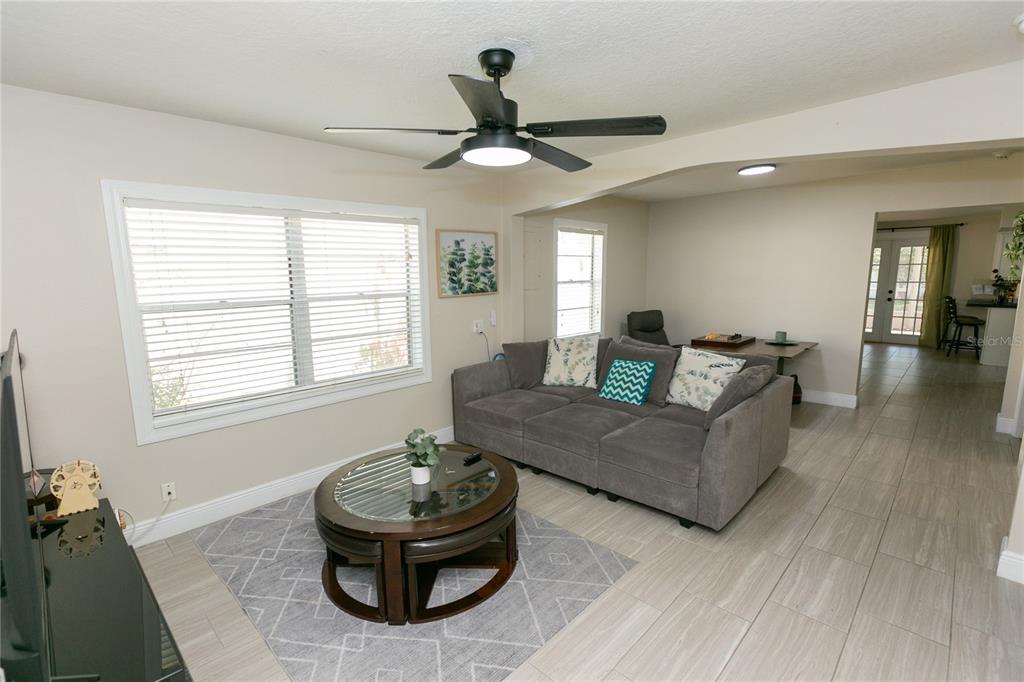 A living room features a gray sofa, a round coffee table, and a ceiling fan — 807 TENNESSEE AVENUE, ST CLOUD, FL