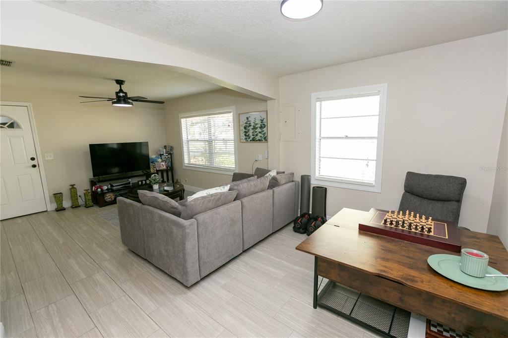 A living room and dining area feature light tile flooring, a gray sectional, and furniture — 807 TENNESSEE AVENUE, ST CLOUD, FL