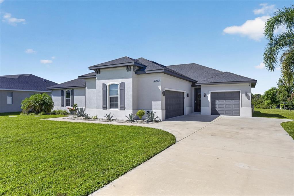 A single-story house with a gray roof, stucco exterior, and a three-car garage — 5218 LAKE VENICE DRIVE, WIMAUMA, FL