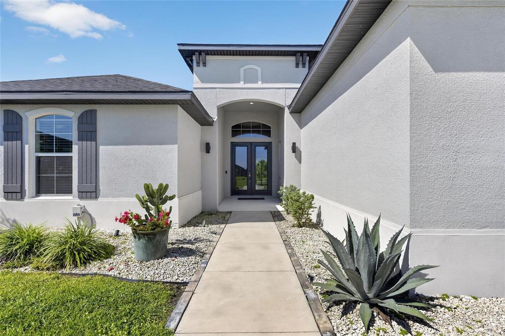 A concrete walkway leads to the double front doors of a light-colored stucco house — 5218 LAKE VENICE DRIVE, WIMAUMA, FL