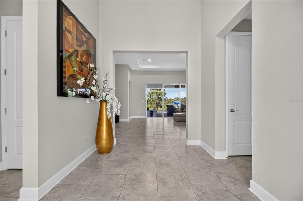 A tiled entryway leads to a living area with large sliding glass doors overlooking a yard — 5218 LAKE VENICE DRIVE, WIMAUMA, FL