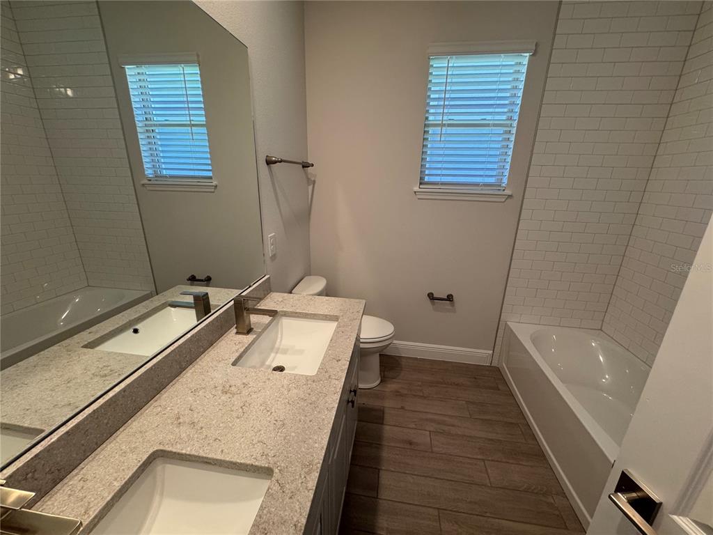 A modern kitchen features white cabinets, stainless steel appliances, a quartz island, and tile flooring — 11857 SHINE VIEW LANE, WINTER GARDEN, FL