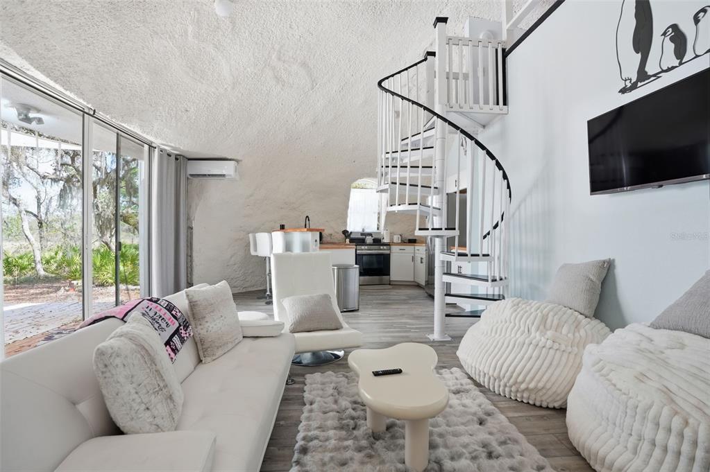 A living room with a spiral staircase, textured dome ceiling, and kitchen in the background — 7570 E RINGER COURT, INVERNESS, FL