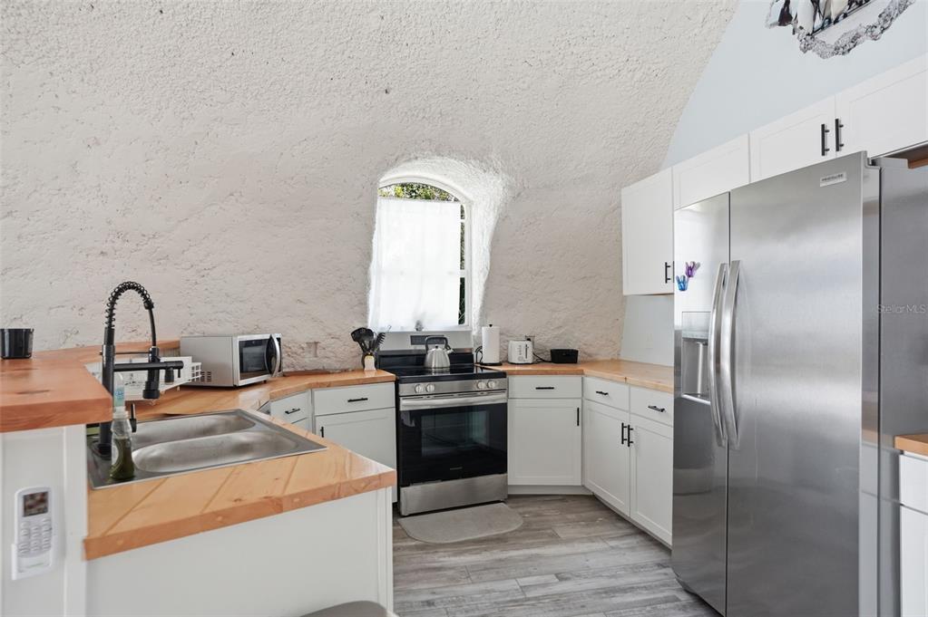 A kitchen with white cabinets, wood countertops, and stainless steel appliances inside a domed room — 7570 E RINGER COURT, INVERNESS, FL