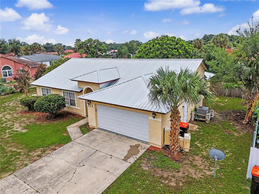 An aerial view of a single-story house with a metal roof and a concrete driveway — 306 OAK TRACK RADIAL, OCALA, FL