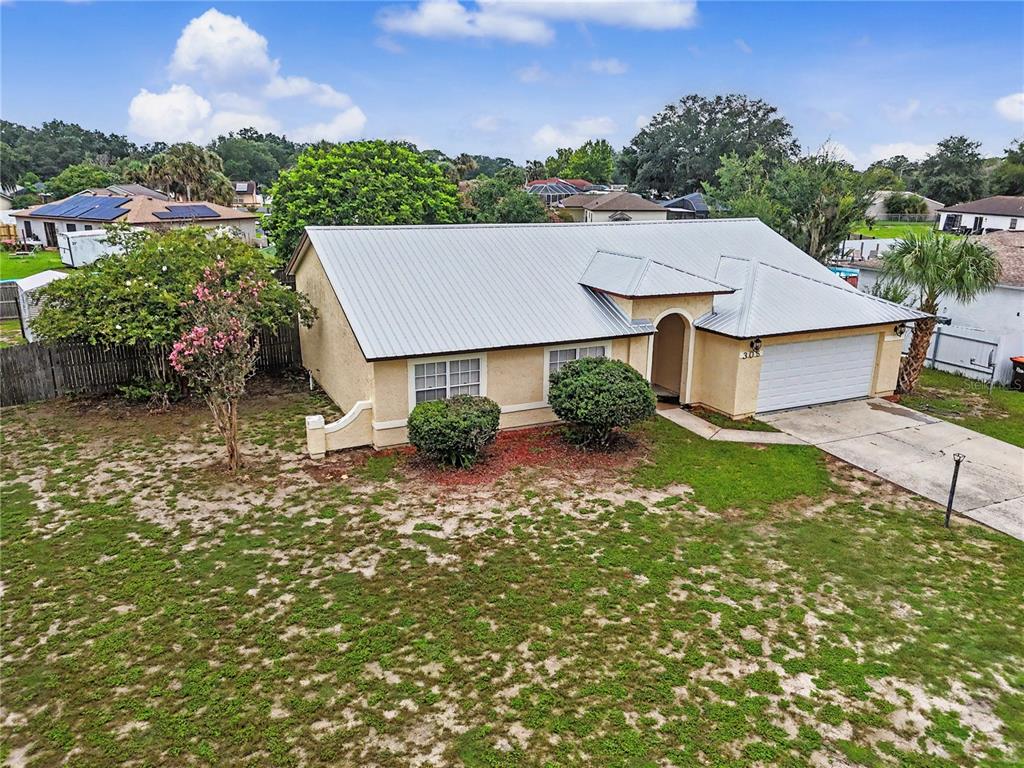 An aerial view of a single-story house with a metal roof and a front garage — 306 OAK TRACK RADIAL, OCALA, FL