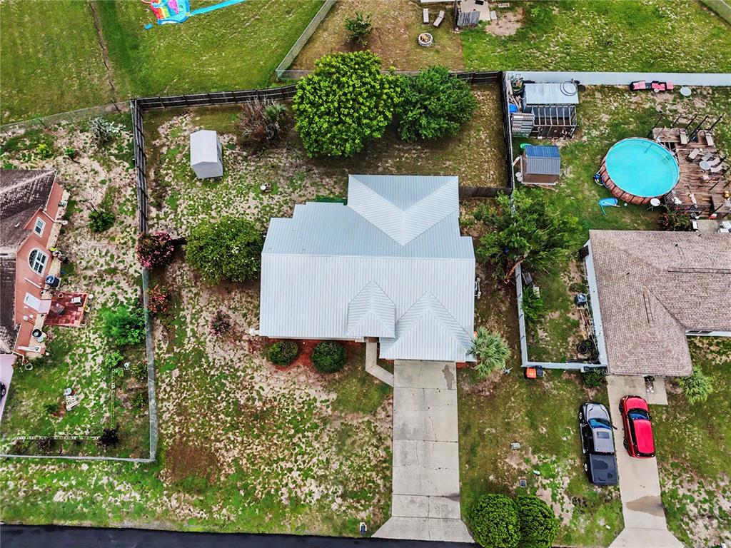 An aerial view shows a house with a metal roof, a driveway, and a backyard pool — 306 OAK TRACK RADIAL, OCALA, FL