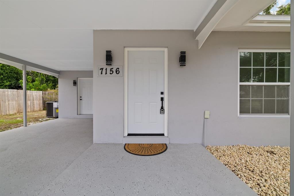 A bright, open-concept living area features white walls, glossy tile flooring, and a modern ceiling light — 7156 SPRING HILL DRIVE, SPRING HILL, FL