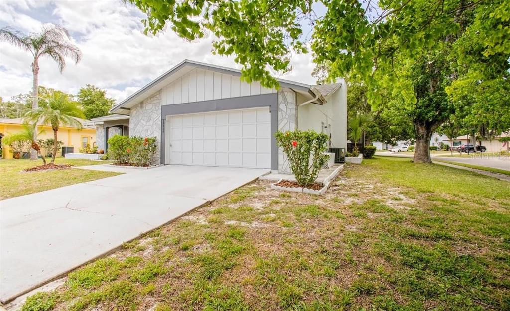 A single-story house with a white garage door, stone-patterned siding, and a concrete driveway — 13309 SHADBERRY LANE, HUDSON, FL