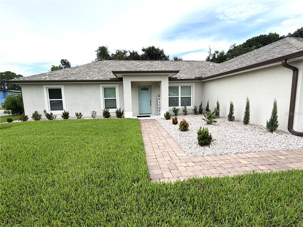 A single-story house with a light-colored exterior, a paved walkway, and a landscaped front yard — 5515 EAGLE WAY, MERRITT ISLAND, FL
