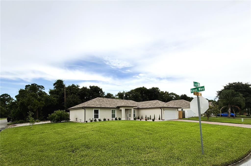 A single-story house with a light-colored exterior and a large lawn sits at a corner — 5515 EAGLE WAY, MERRITT ISLAND, FL