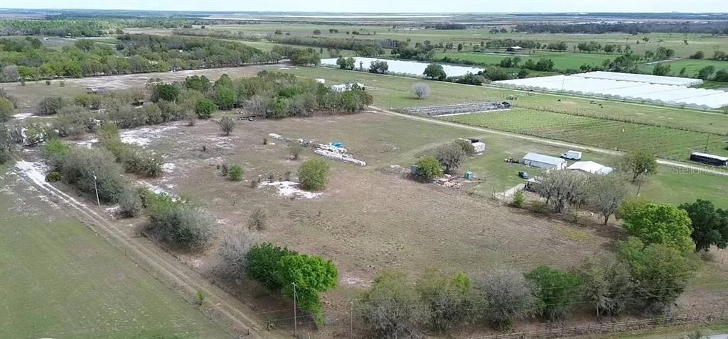 An aerial view shows a large, grassy rural lot with scattered trees and small buildings — 30620 TAYLOR GRADE ROAD, DUETTE, FL