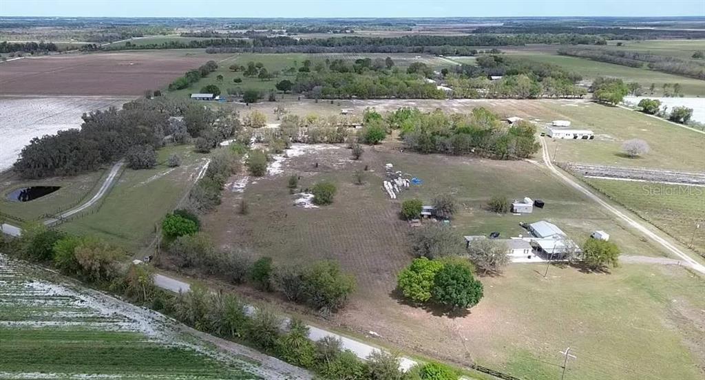 An aerial view shows a rural property with a house, outbuildings, trees, and open fields — 30620 TAYLOR GRADE ROAD, DUETTE, FL