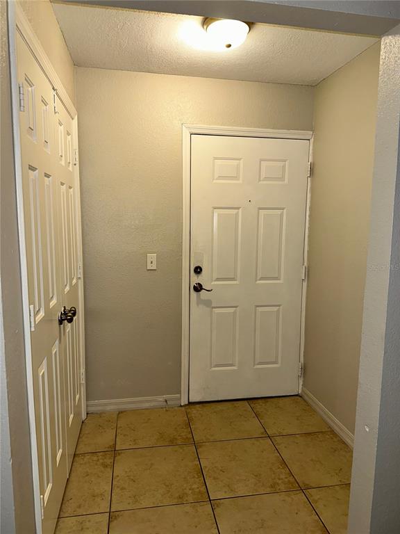 An entryway features a white door, a closet with double doors, and beige tile flooring — 4184 VERSAILLES DRIVE UNIT 4184D, ORLANDO, FL