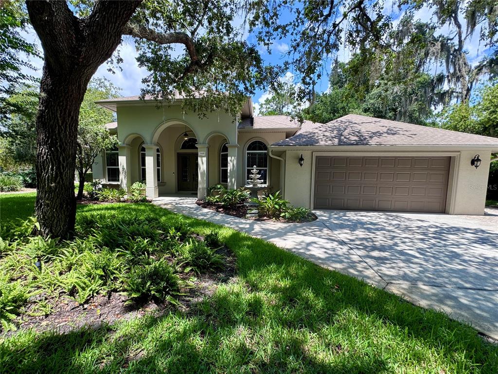 A single-story house with a tan stucco exterior, arched entryway, and a two-car garage — 3448 ACOMA DRIVE, ORMOND BEACH, FL