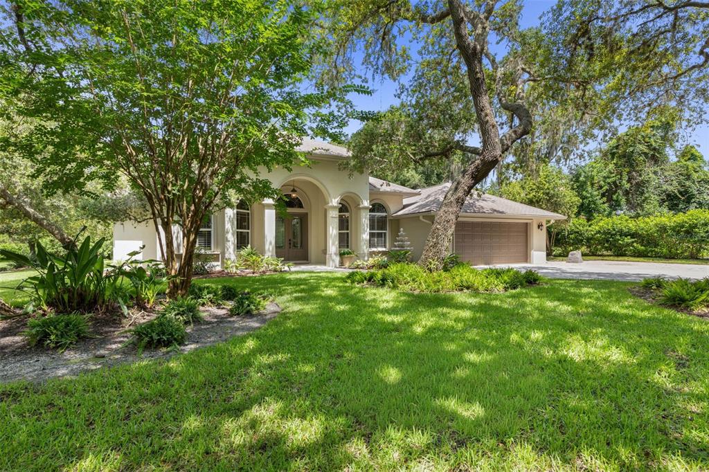 A single-story house with a beige stucco exterior, arched entryway, and a two-car garage — 3448 ACOMA DRIVE, ORMOND BEACH, FL