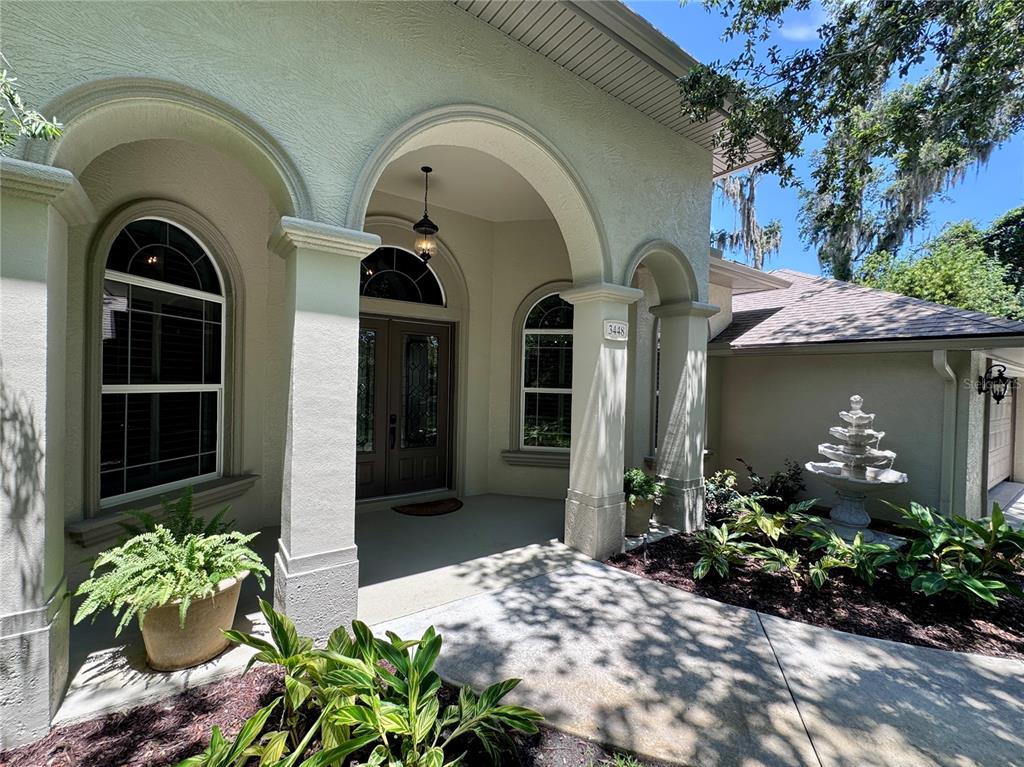 The front entrance of a house features arched doorways, a double door, and a stone fountain — 3448 ACOMA DRIVE, ORMOND BEACH, FL