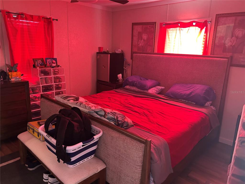 A bedroom features a large bed with a red comforter, purple pillows, and red lighting — 231 TANGLEWOOD DRIVE, APOPKA, FL