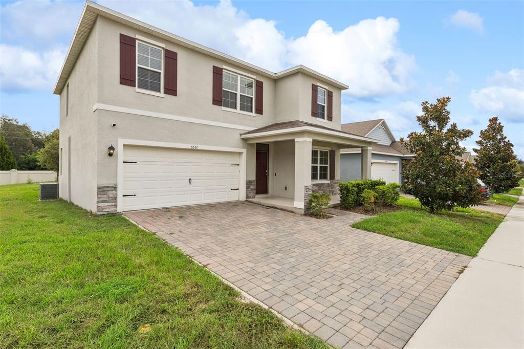 A two-story house with a paved driveway, a two-car garage, and a covered front porch — 5551 PALOMINO PLACE, APOPKA, FL