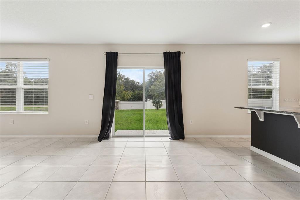 A bright room with light tile flooring, two windows, and a sliding glass door — 5551 PALOMINO PLACE, APOPKA, FL
