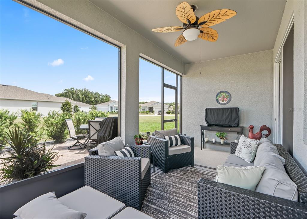 A screened-in patio features wicker furniture, a ceiling fan, and views of a grassy yard — 5209 NW 46TH LANE RD, OCALA, FL