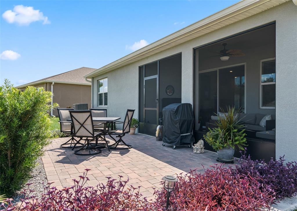A paved patio features outdoor dining furniture and a grill next to a screened-in porch — 5209 NW 46TH LANE RD, OCALA, FL