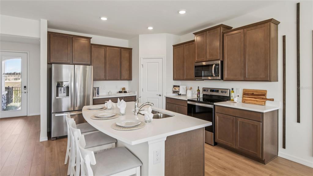 A kitchen features brown cabinets, white countertops, a central island, and stainless steel appliances — 11233 DUCKLING WAY, WEEKI WACHEE, FL