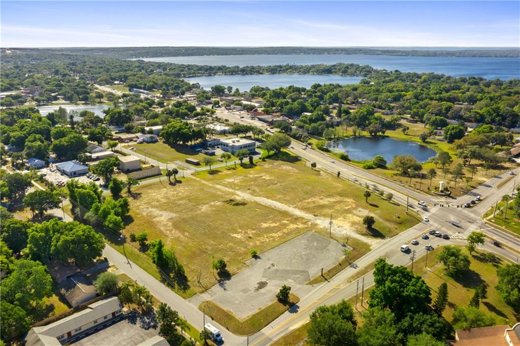 An aerial view shows a large, vacant, grassy lot situated near a lake and roads — 901 12TH STREET, CLERMONT, FL